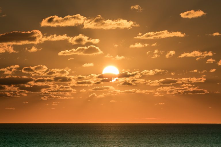 Coucher de soleil sur l'océan avec un ciel orange et des nuages
